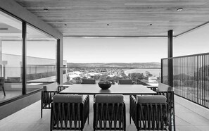 Ein moderner Essbereich mit Tisch und Stühlen, einem großen Fenster und Blick auf eine Stadtlandschaft.