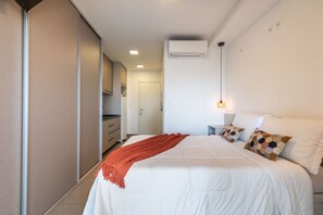 Ein Hotelzimmer mit Bett, Nachttisch, Lampe und Kleiderschrank.