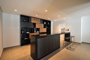 A modern kitchen with a central island, bar stools, and built-in shelving. - Mc601-1810 You Faria Lima (São Paulo)