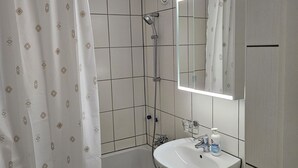 A bathroom with a bathtub, a shower, a sink, and a toilet. - Parkareal Davos Vacation Rental for 2 People: Comfortable, Cozy, and Centrally Located (Davos Platz)