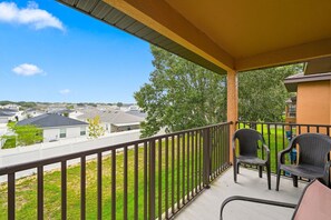 A balcony with a view of a residential area, a railing, and two chairs. - Bright & Airy 4BR Disney Home w/ Patio & Parking (Davenport)