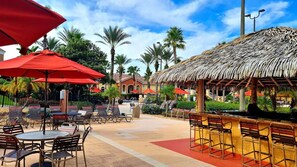 An outdoor seating area with tables and chairs, a thatched-roof structure, and palm trees. - Bright & Airy 4BR Disney Home w/ Patio & Parking (Davenport)