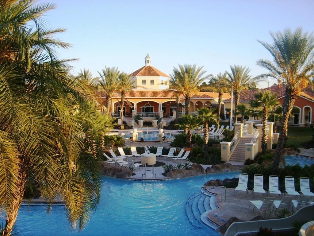 A resort with a swimming pool, palm trees, and a building with a dome roof.