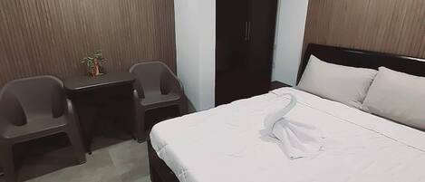 Habitación de hotel con cama, dos sillas, una mesita y un armario.