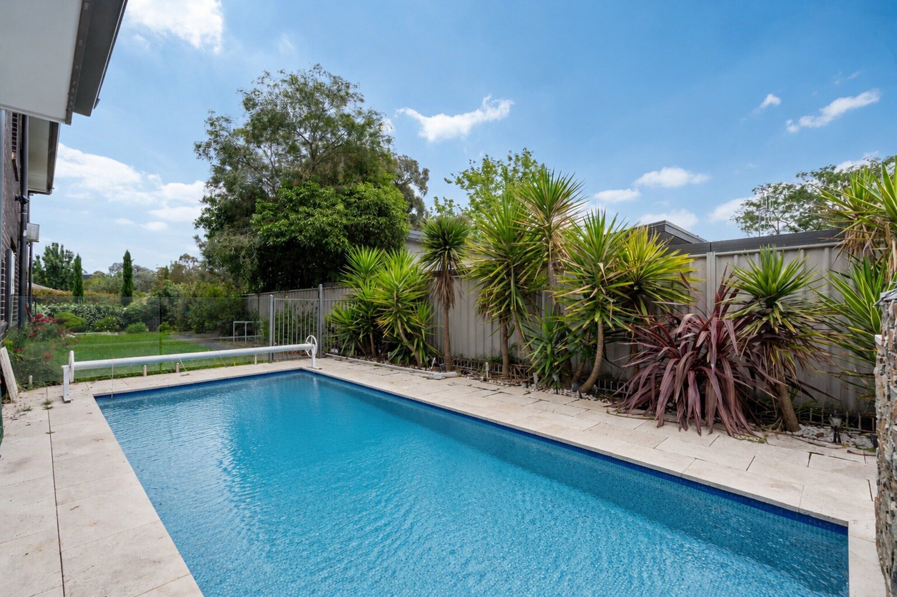 A rectangular swimming pool with a clear blue water surface, surrounded by a concrete deck.