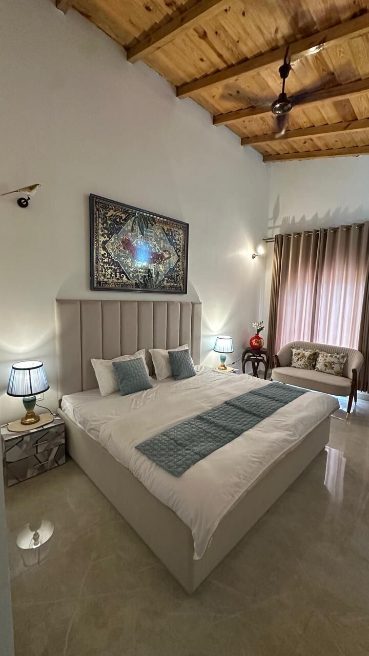 Un dormitorio con una cama grande, ventilador de techo, un adorno en la pared, un sofá y cortinas.