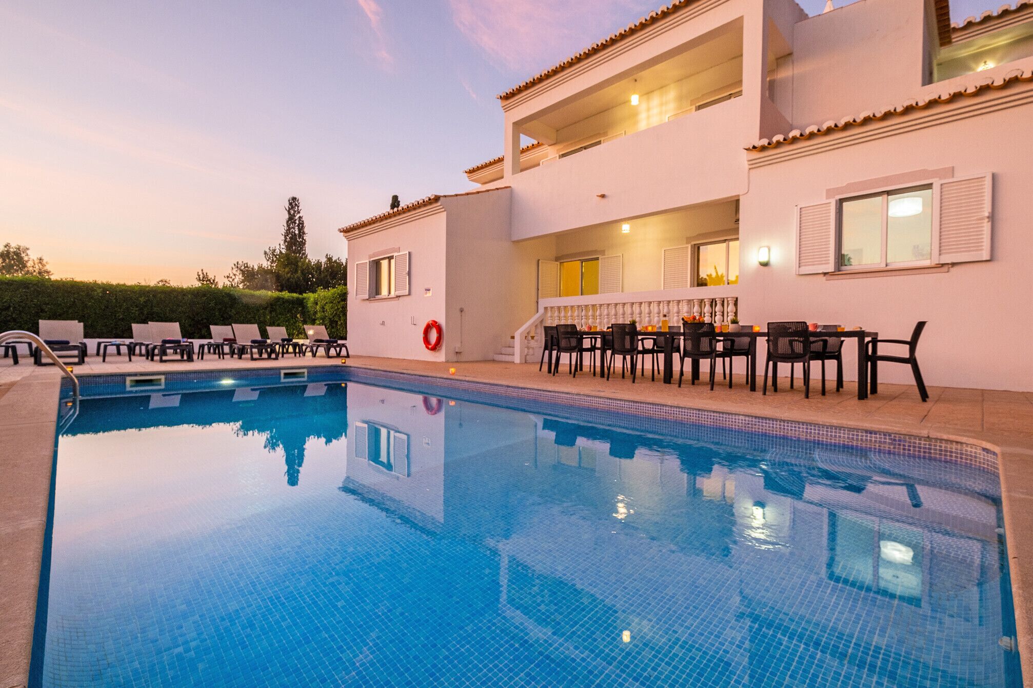 A swimming pool with lounge chairs and a dining area with tables and chairs.