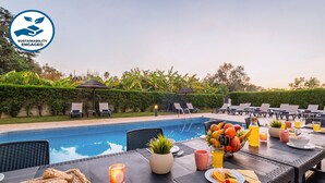 A poolside dining area with a table set for breakfast, including fruits, bread, and beverages. - Holiday villa with BBQ and heatable pool (Albufeira)
