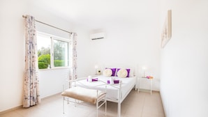 A bedroom with a bed, bedside table, and a window with curtains. - Holiday villa with BBQ and heatable pool (Albufeira)