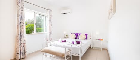 A bedroom with a bed, bedside table, and a window with curtains.