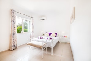 A bedroom with a bed, bedside table, and a window with curtains. - Holiday villa with BBQ and heatable pool (Albufeira)