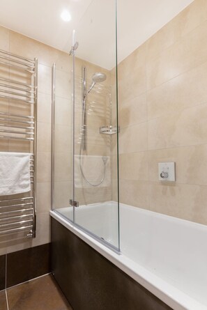 Une salle de bain moderne avec une douche à parois de verre, une baignoire blanche et un porte-serviettes.