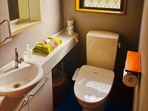 A bathroom with a sink, toilet, and a towel dispenser.