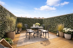 A patio with a round table and chairs, surrounded by potted plants and a decorative hedge. - Knightsbridge & South Kensington 2 Bed,2 Bath with Private Garden Near Hyde Park (London)