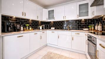 A modern kitchen with white cabinets, black backsplash, and stainless steel appliances.