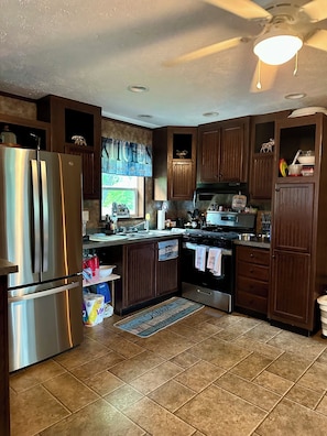 A kitchen with wooden cabinets, stainless steel appliances, and a window with a view.