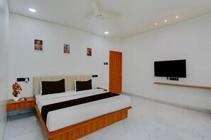 Une chambre à coucher avec un lit, une table de chevet, un téléviseur et des œuvres d’art accrochées au mur.