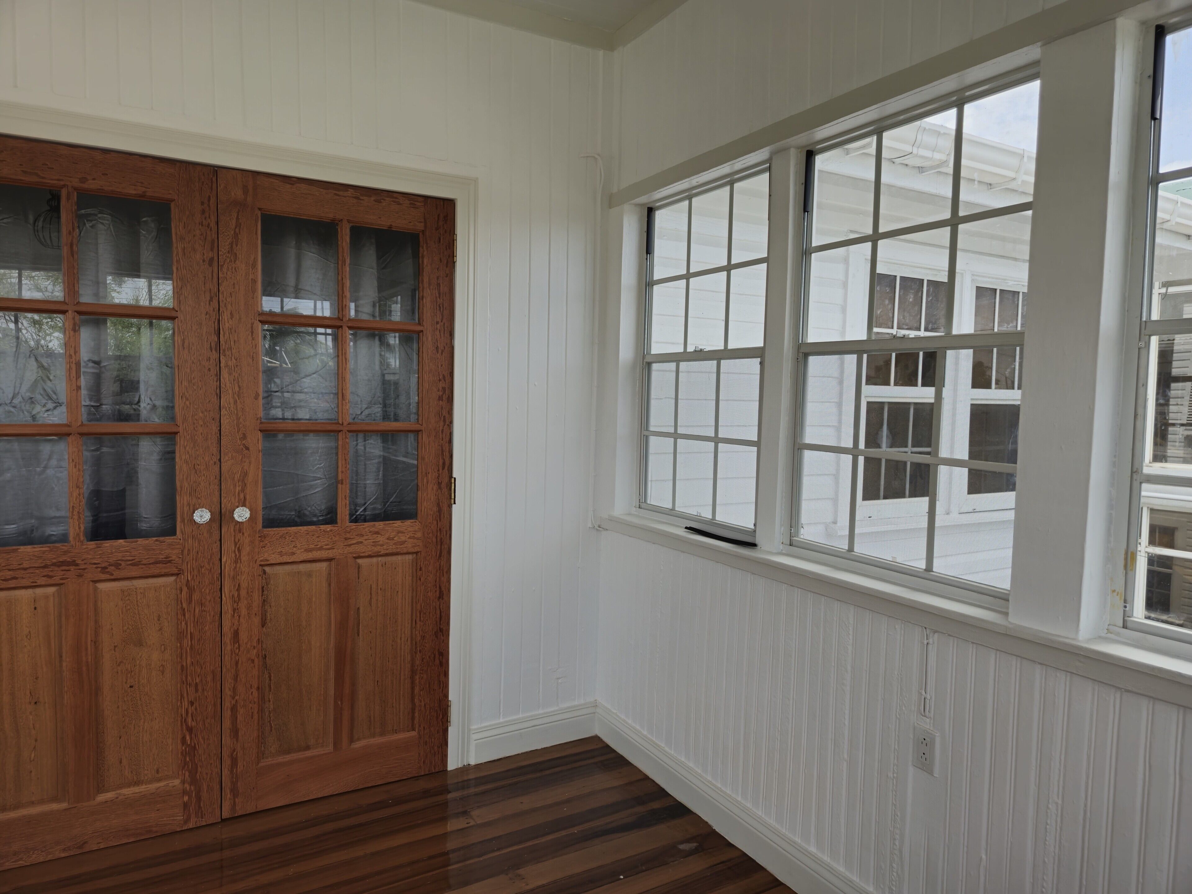 A room with a wooden door and a large window.