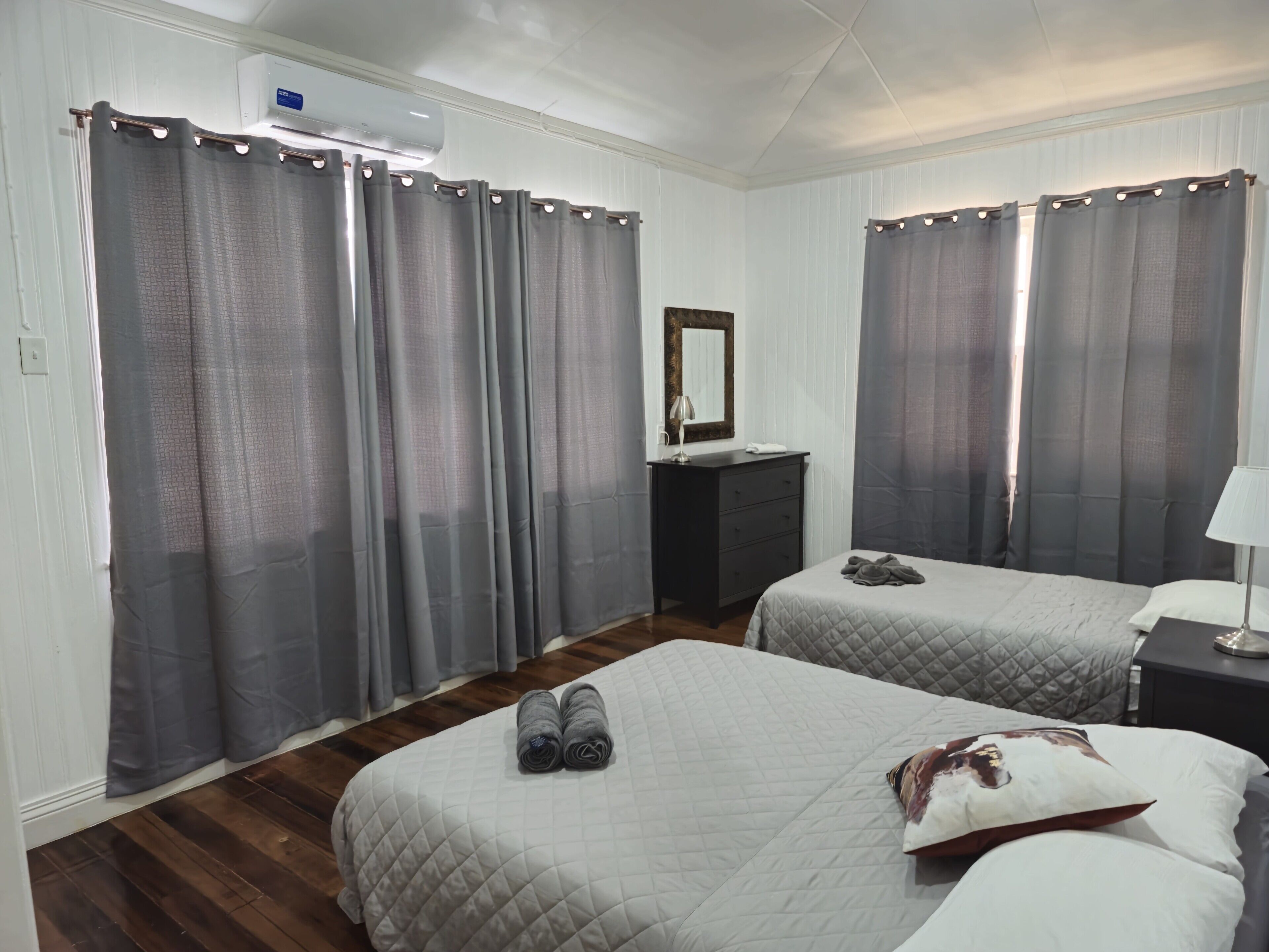 A hotel room with two beds, a dresser, a mirror, and a nightstand.