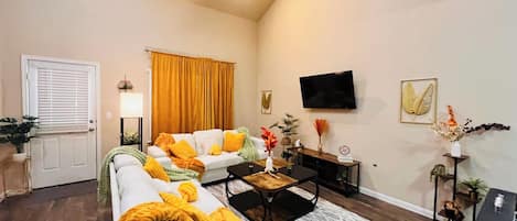 Una sala de estar con sofá, mesa de centro, televisor y una puerta.