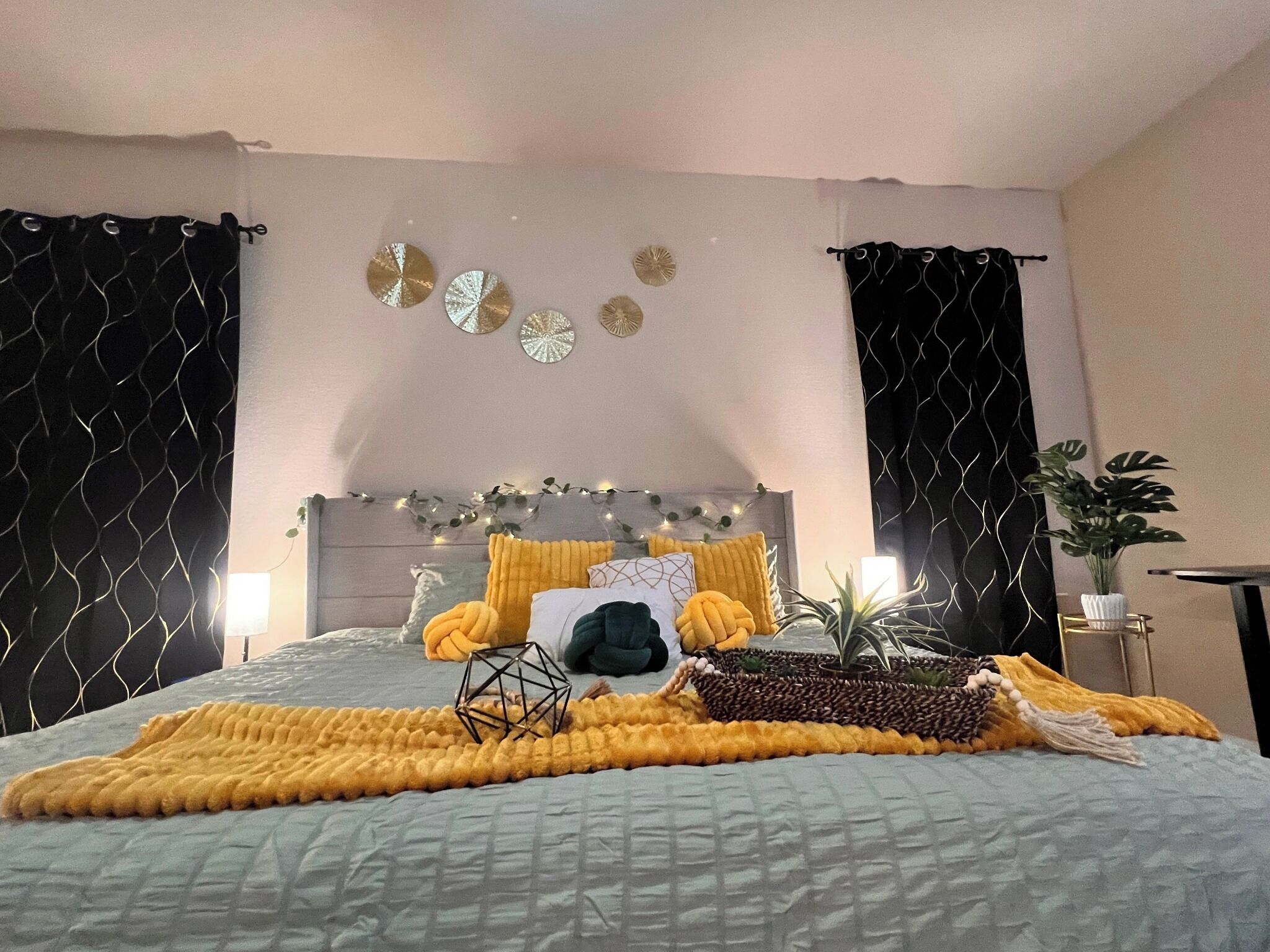 Een slaapkamer met een bed, decoratieve wandkunst en een plant.