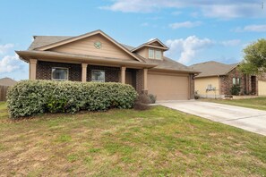 A two-story house with a brick facade, a front porch, and a well-maintained lawn.