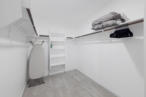 A compact bathroom with a toilet, a shelf with toiletries, and a hanging rack for clothes.