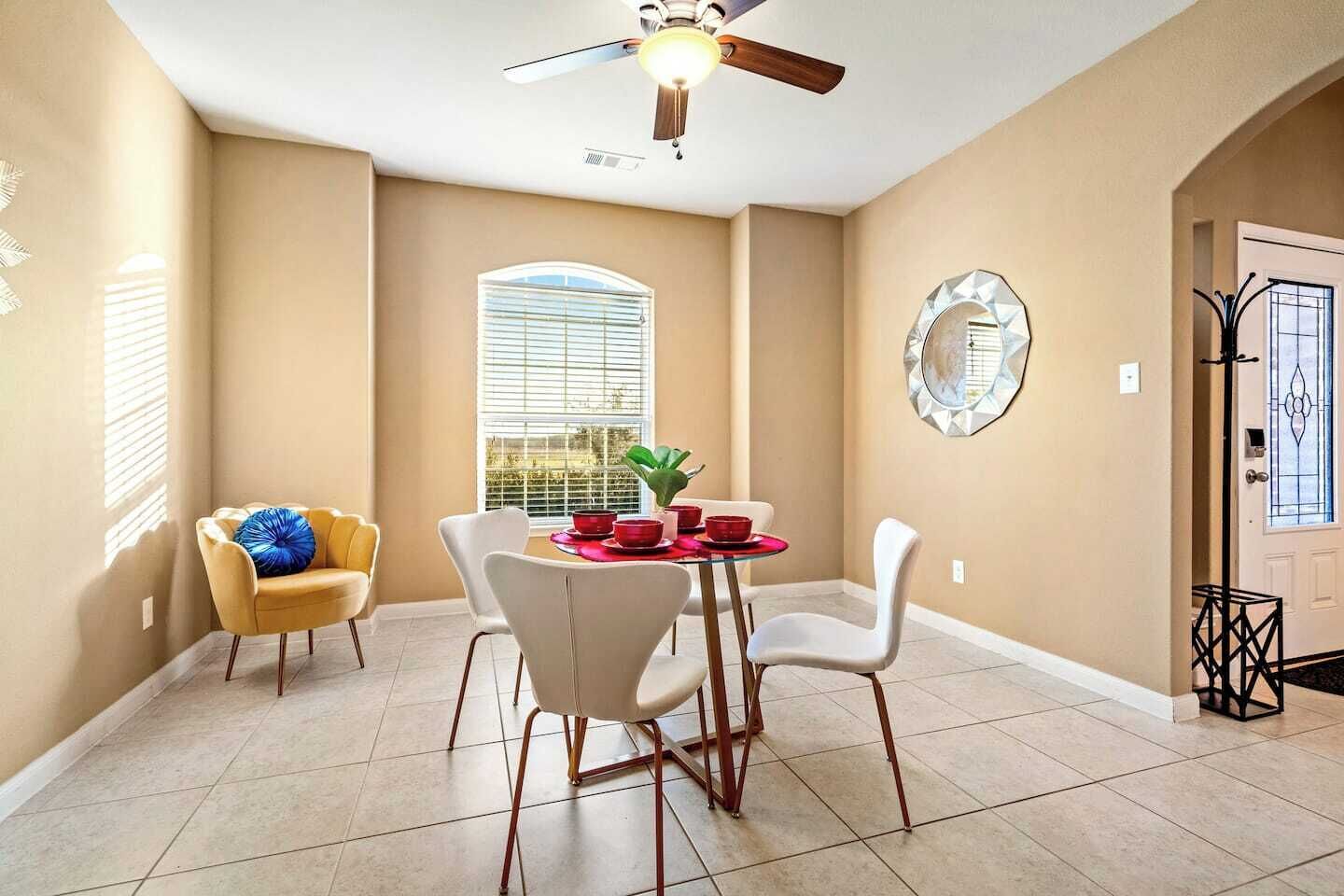 A dining area with a table, chairs, and a ceiling fan.