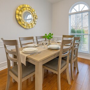 Une salle à manger avec une table en bois dressée pour six personnes, entourée de six chaises.