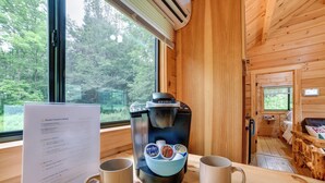A wooden cabin interior with a Keurig coffee maker, two mugs, and a guest check-in sheet on the table. - Private Catskills Campsite! Tiny Cabin + Airstream (Sidney Center)