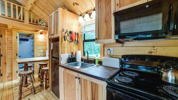 A compact kitchen with wooden cabinetry, a stove, and a sink.
