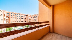 Ein Balkon mit Holzbalkon und Blick auf einen Innenhof mit Gebäuden im Hintergrund.