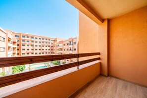 Ein Balkon mit Holzbalkon und Blick auf einen Innenhof mit Gebäuden im Hintergrund.