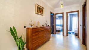 Ein Hotelzimmer mit einem hölzernen Schminktisch, einer Topfpflanze und einem Gemälde an der Wand.