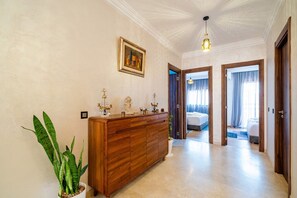 Ein Hotelzimmer mit einem hölzernen Schminktisch, einer Topfpflanze und einem Gemälde an der Wand.