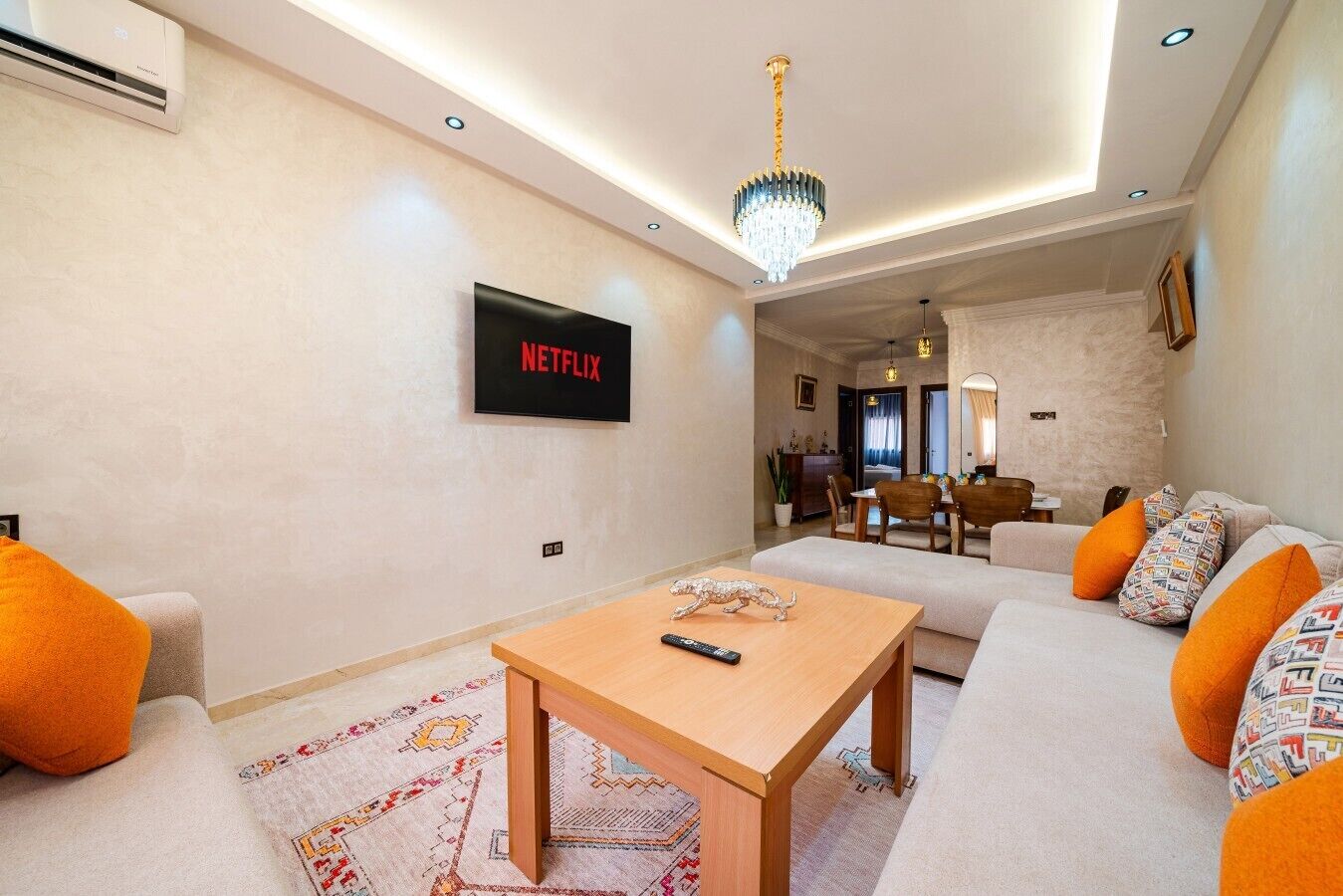Een moderne woonkamer met een bank, een salontafel en een aan de muur bevestigde televisie.