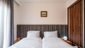 Ein Hotelzimmer mit zwei Betten, einem Kopfteil, einem Nachttisch, einem gerahmten Bild und einem Holzschrank.
