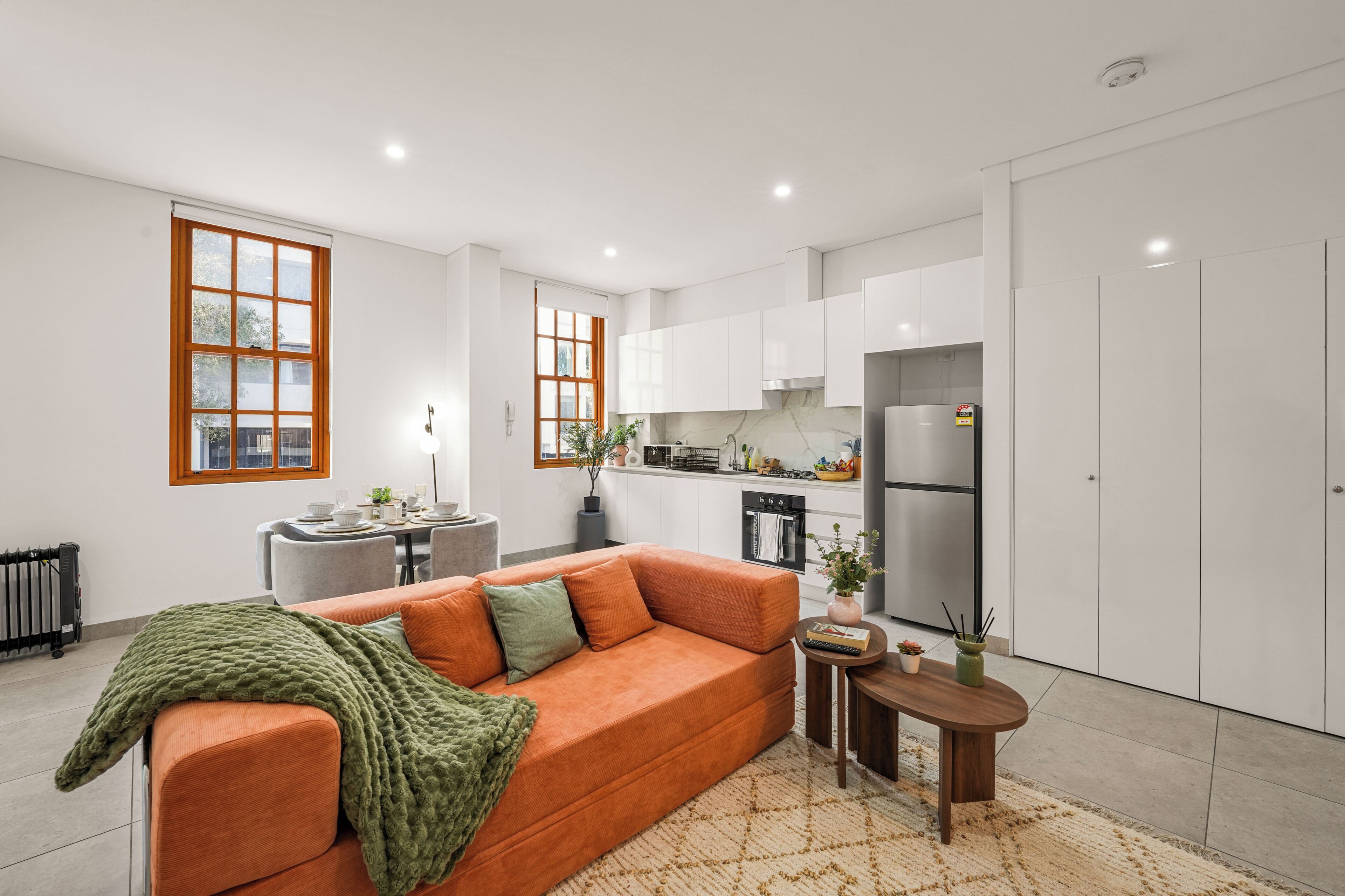 A modern living room with a sofa, a coffee table, and a dining area with a table set for four.