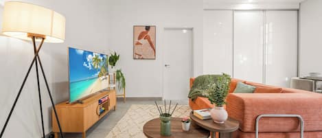 Un salon moderne avec un téléviseur à écran plat, un canapé, une table basse et un lampadaire.