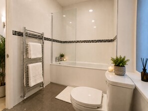 Uma casa de banho moderna com cabine de duche em vidro, sanita branca e banheira.