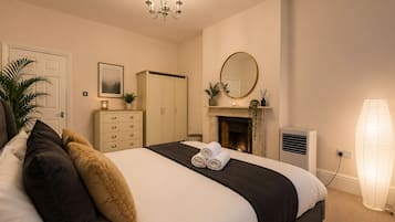 Quarto com cama, penteadeira, espelho, lareira e abajur.