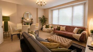 Sala de estar com sofá, apoio para os pés e área de jantar com cadeiras e mesa.