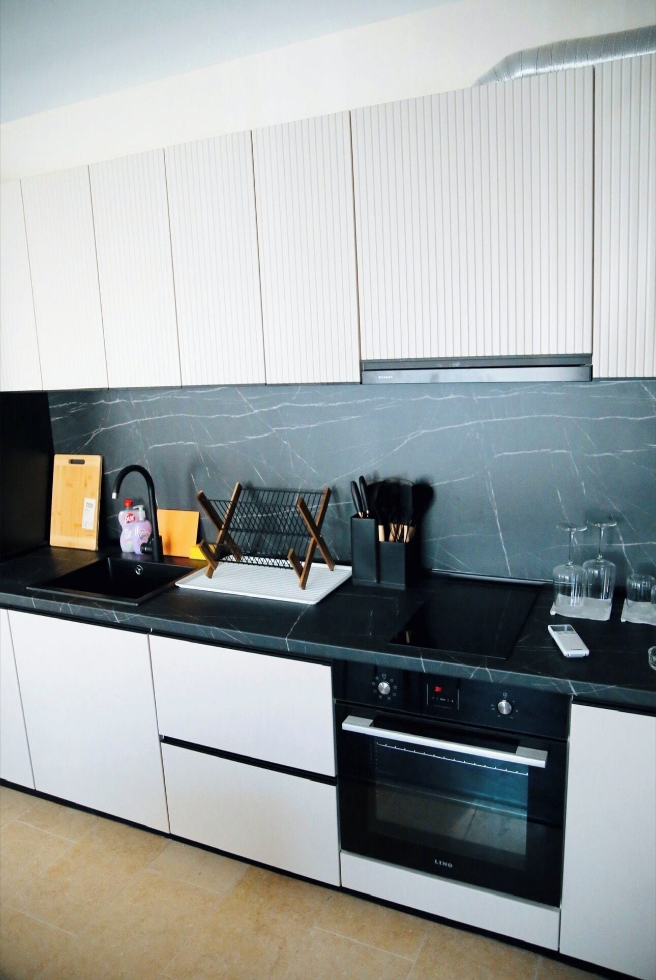 A modern kitchen with a black countertop, stainless steel appliances, and white cabinetry.