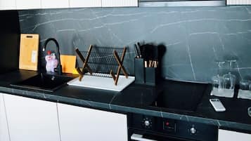 A modern kitchen with a black countertop, stainless steel appliances, and white cabinetry.