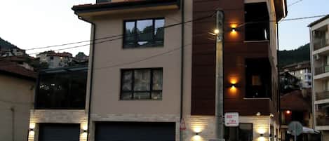 Un edificio moderno de dos pisos con un garaje, una señal de paso para peatones y un poste de luz.