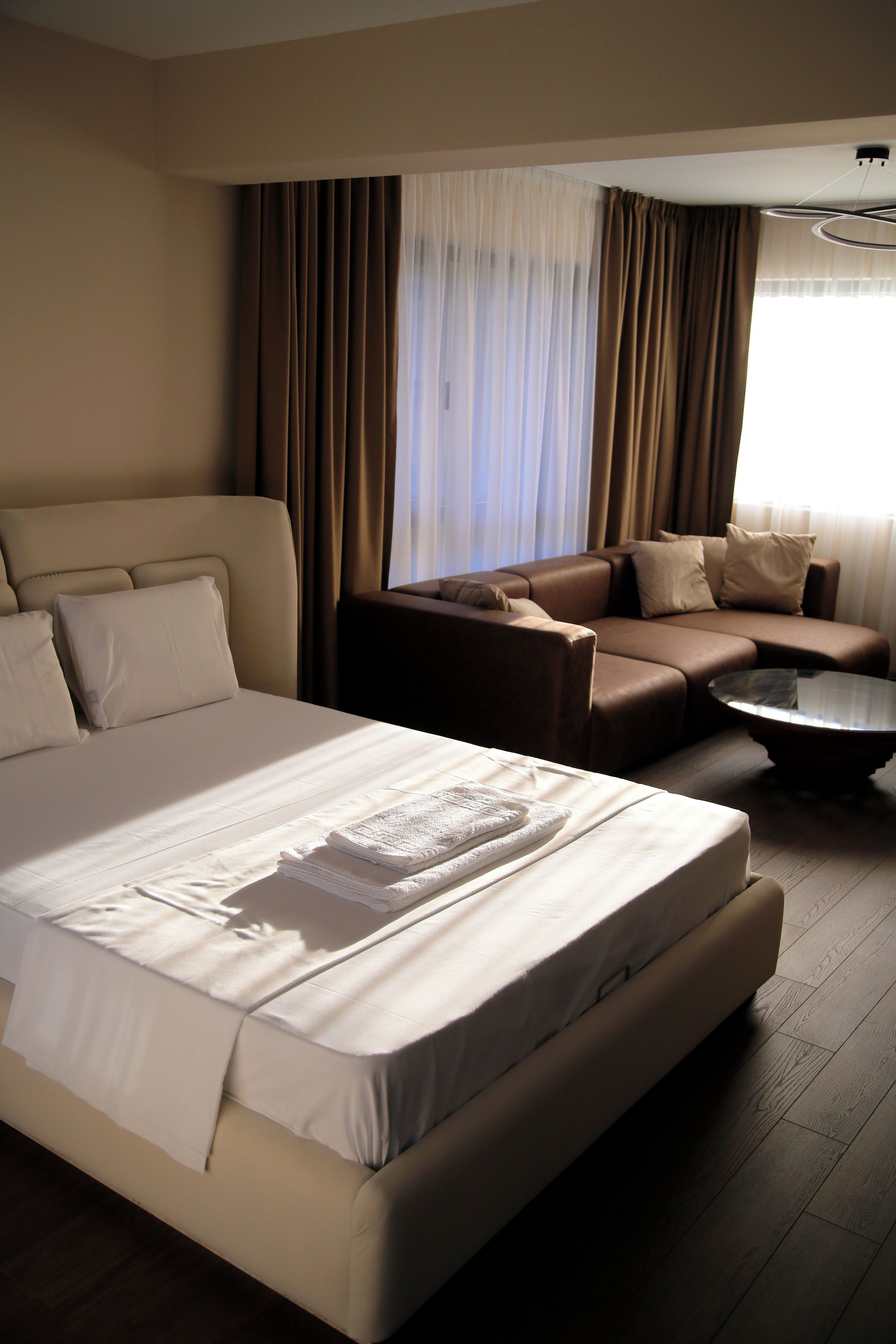 Une chambre d’hôtel avec un grand lit, un canapé, une petite table et une fenêtre avec des rideaux.