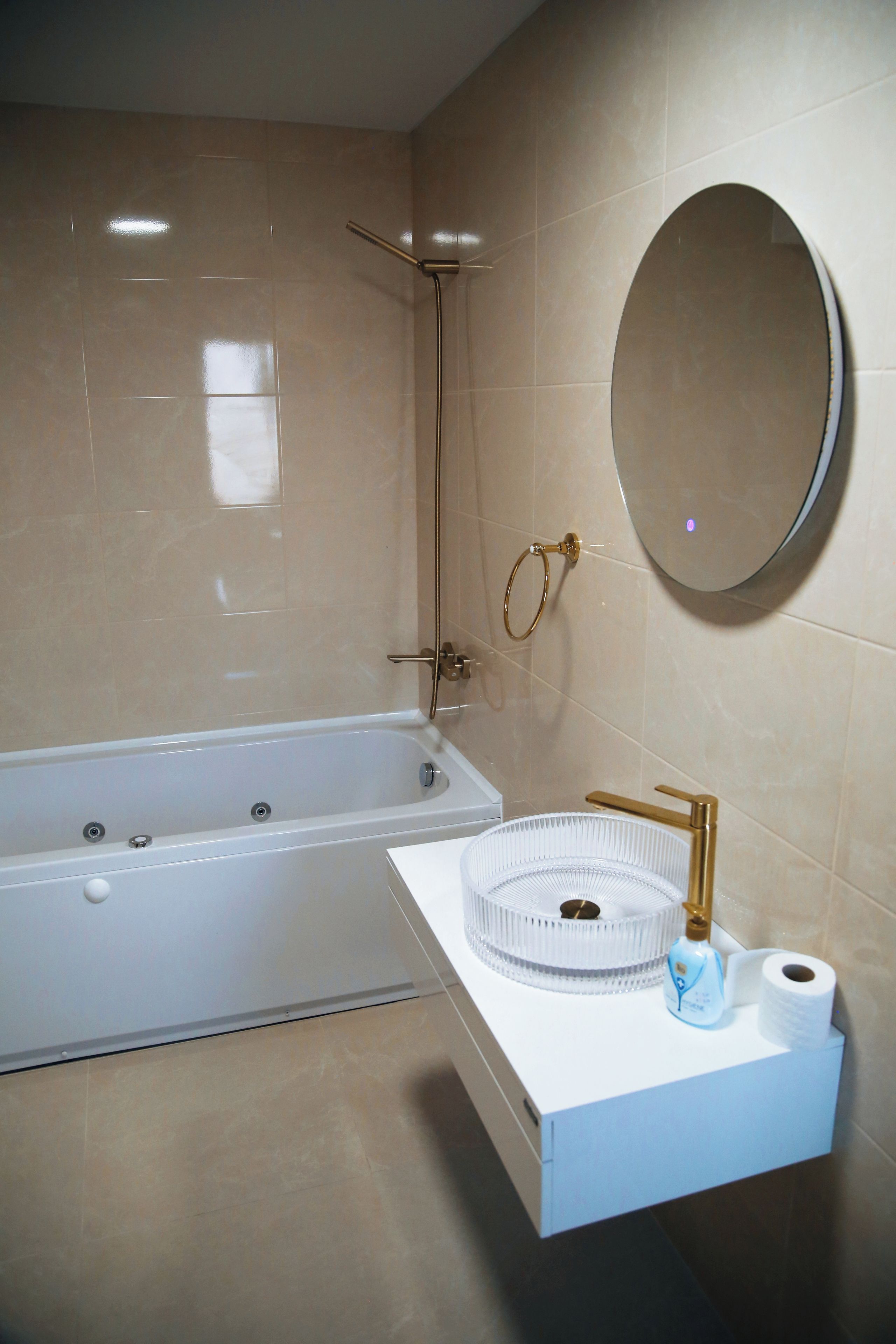 A bathroom with a bathtub, a sink with a round mirror, and a toilet.