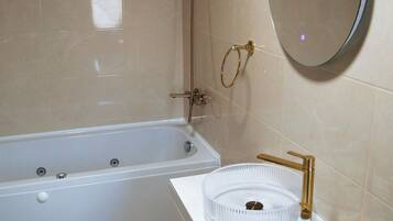 A bathroom with a bathtub, a sink with a round mirror, and a toilet.