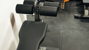 A row of black exercise benches in a gym with various fitness equipment in the background.