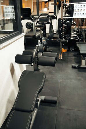 A row of black exercise benches in a gym with various fitness equipment in the background. - Nature Heals by Todoroff (Devin)